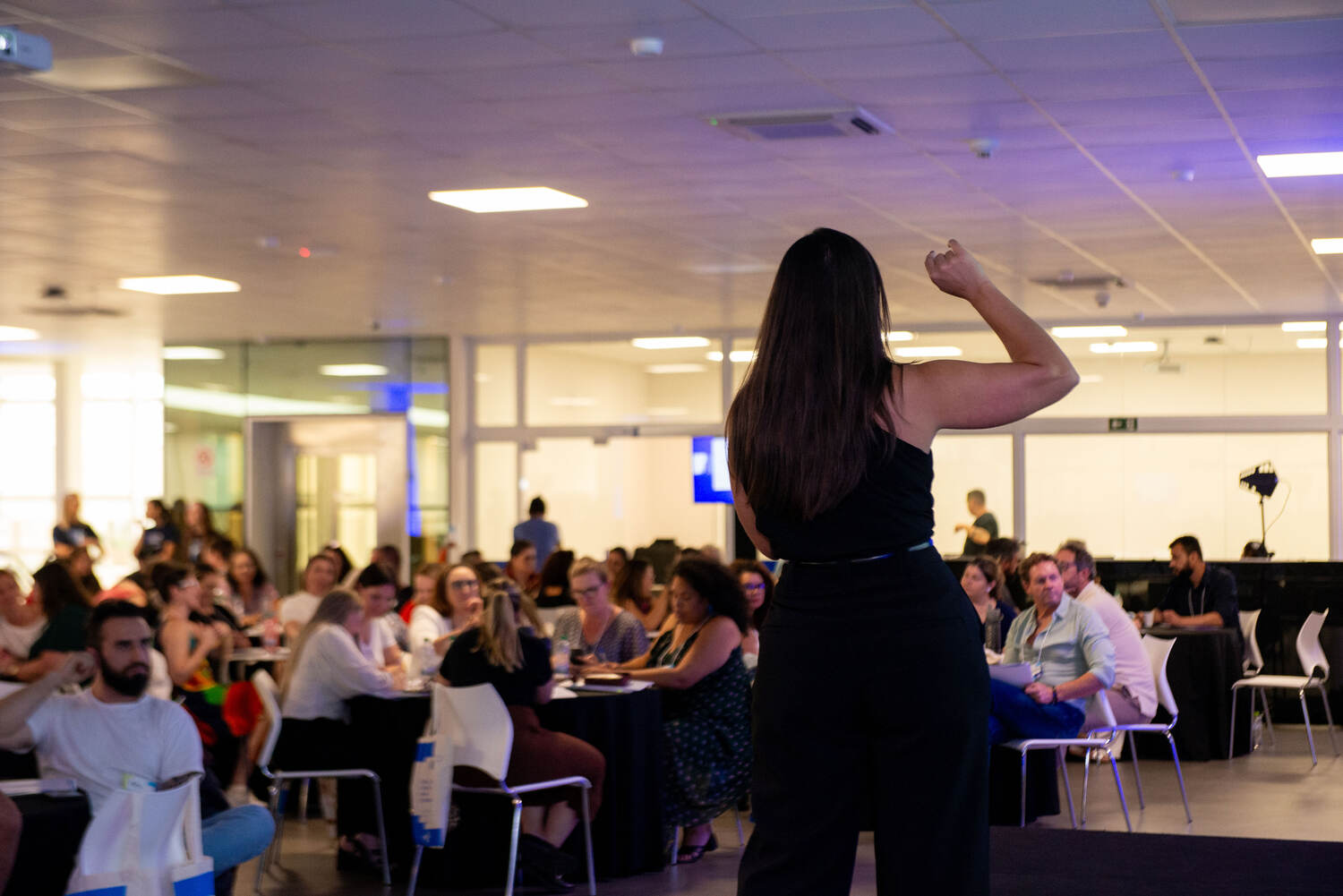 Mônica Carvalho conduzindo treinamento corporativo para plateia lotada